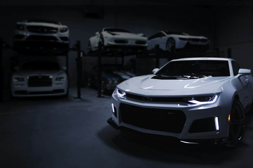 White Camaro and luxury cars in a specialty garage — car wrap shop photo